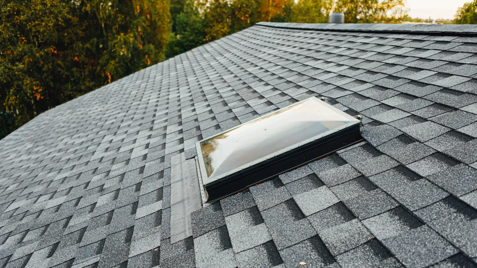Domed skylight installed on a dark gray asphalt shingle roof
