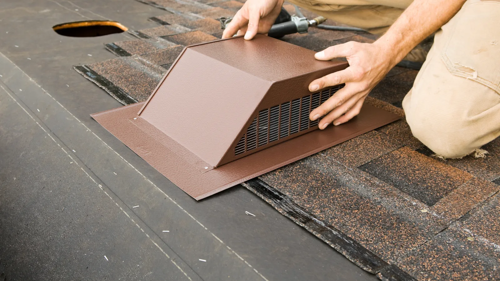 A roofer positioning a brown vent over a roof opening