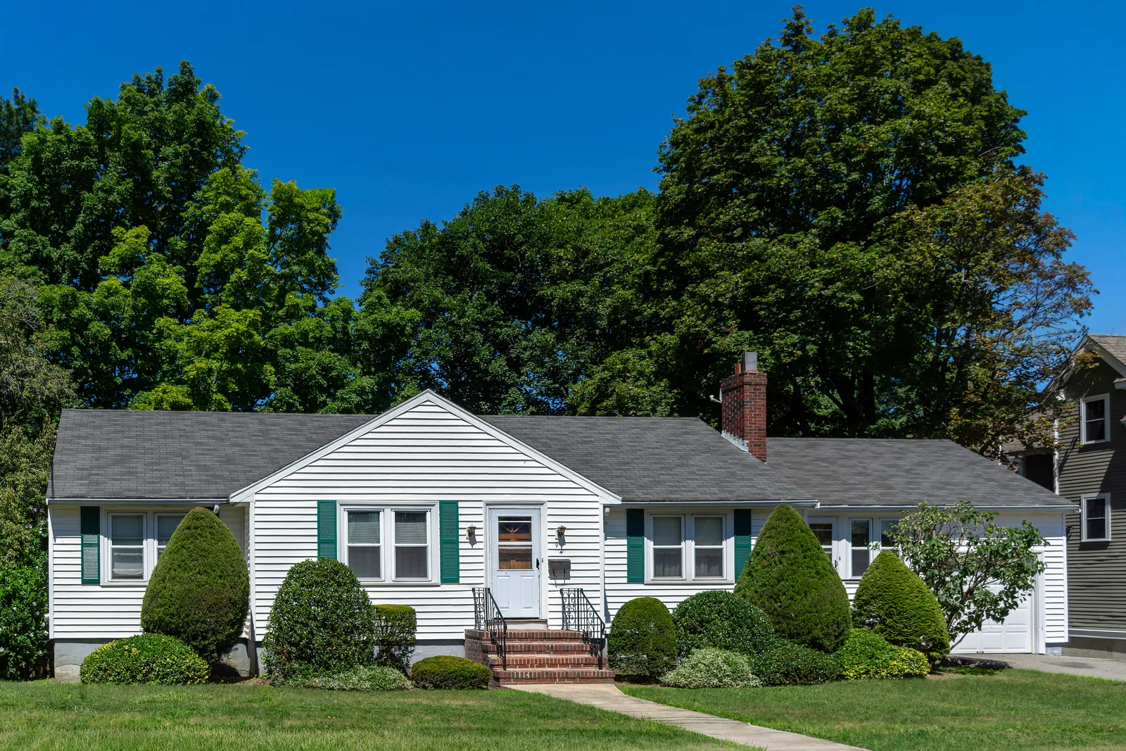 Brick chimney on a white house under a dark asphalt shingle roof